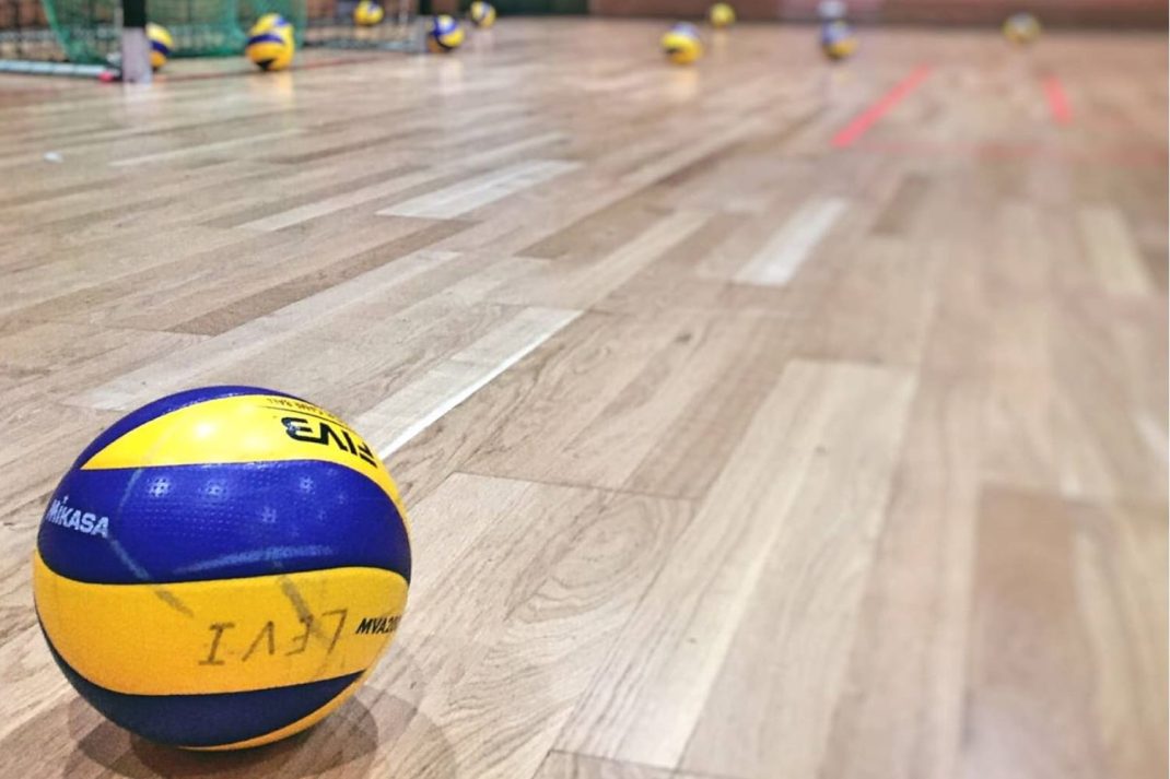 Ein Volleyball liegt auf dem Hallenfußboden.