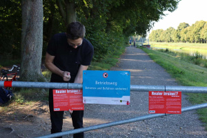 Michael Neuhaus bringt ein Hinweisschild der Linksfraktion an der Schranke am Ratsholzdeich an. Foto: Ralf Julke