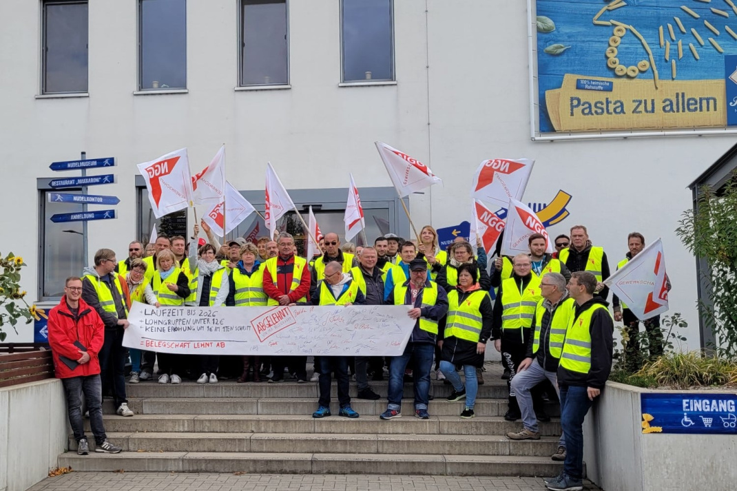 Streikende der Firma Riesa Nudeln mit Transparent und Fahnen auf einer Treppe