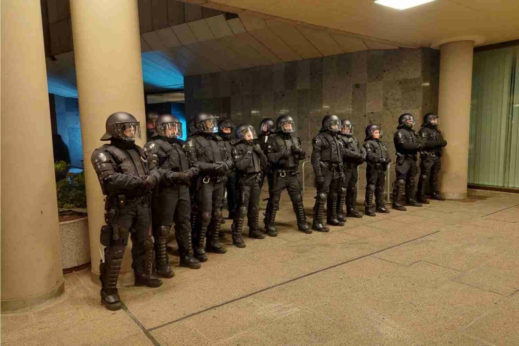 Polizisten mit Helmen stehen in einer Reihe und sperren einen Durchgang am Gewandhaus ab