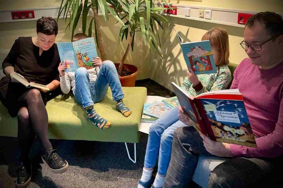 Der Bürgermeister und eine Frau lesen zwei Kindern etwas vor