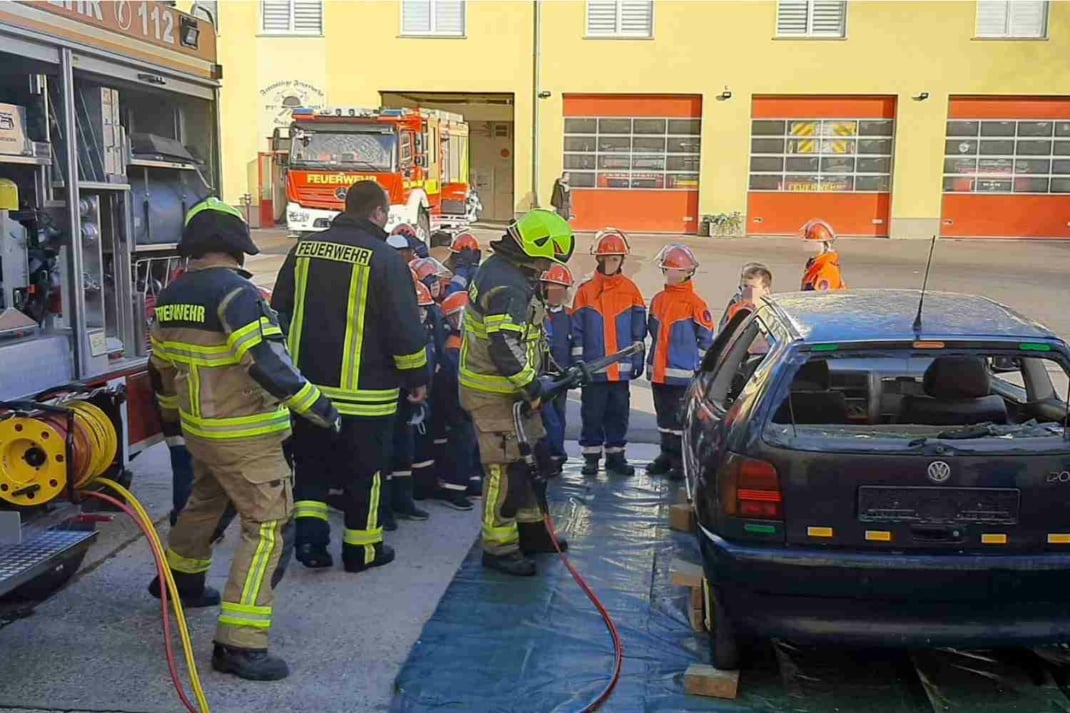 Feuerwehrmänner und Feuerwehrkinder bei einer Übung an einem Autowrack