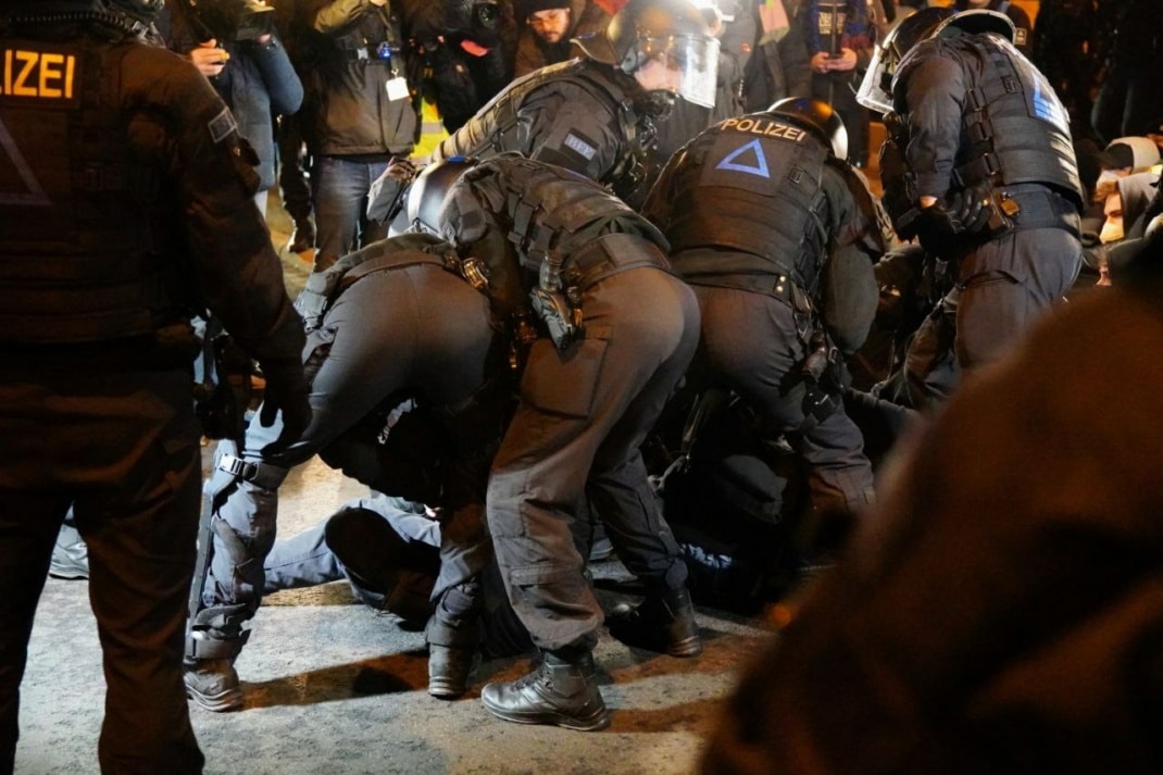 Die Polizei räumt eine Straßenblockade mit körperlichem Zwang und Schmerzgriffen.