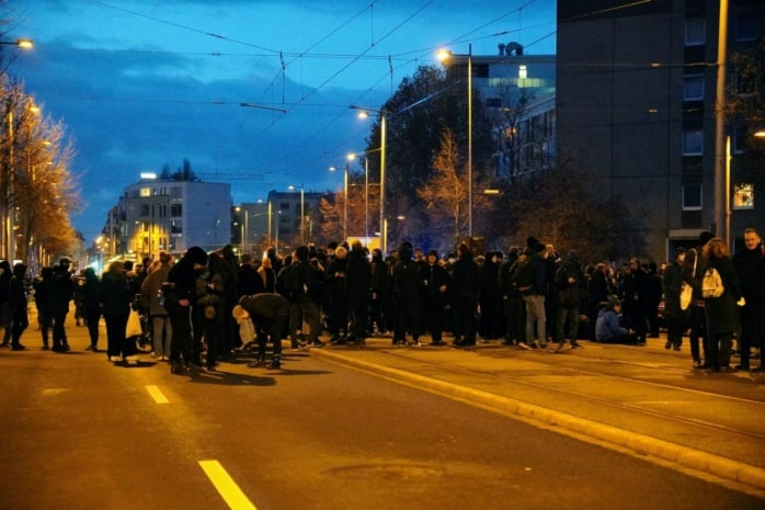 Mehrere Dutzend Menschen stehen und sitzen auf der Friedrich-Ebert-Straße.