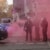 Pinker Rauch steht zwischen zwei Polizeiautos auf, dazwischen stehen mehrere Polizist*innen.