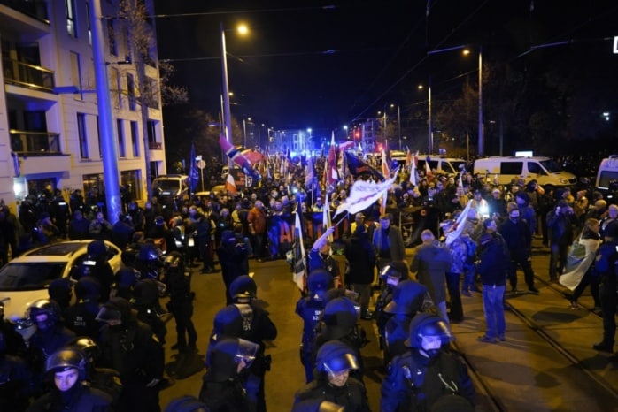 Hunderte Menschen stehen und sitzen auf der Straße.
