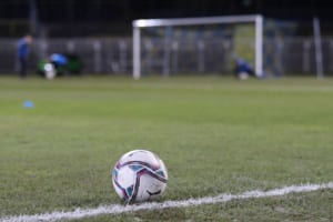 Ein Fußball liegt direkt neben der Seitenaus-Linie auf dem grünen Spielfeld. Im Hintergrund ist ein Fußballtor zu erkennen. Foto: Jan Kaefer
