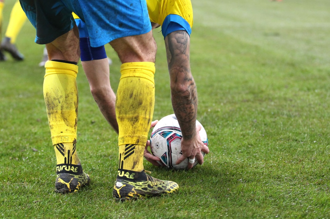 Ein Spieler des 1. FC Lok Leipzig in blau-gelber Spielkleidung, legt sich den Fußball für einen Freistoß zurecht. Foto: Jan Kaefer