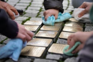 Schüler/-innen polieren Stolpersteine (Gedenksteine für jüdische Menschen aus Messing) in der Leipziger Innenstadt.