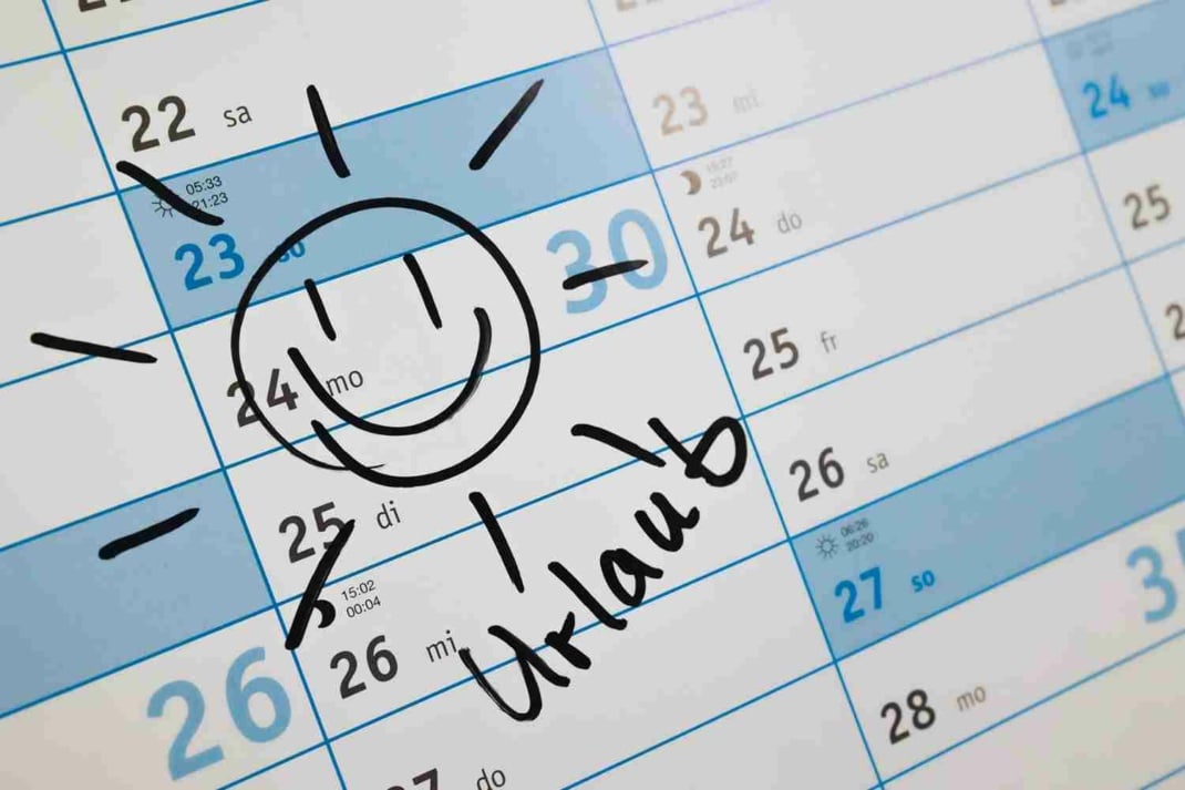 Ein Kalender mit einer aufgemalten lachenden Sonne und dem Wort Urlaub darunter
