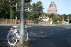 Blick auf ein sogenanntes Geisterfahrrad an der Prager Straße mit Völkerschlachtdenkmal im Hintergrund.
