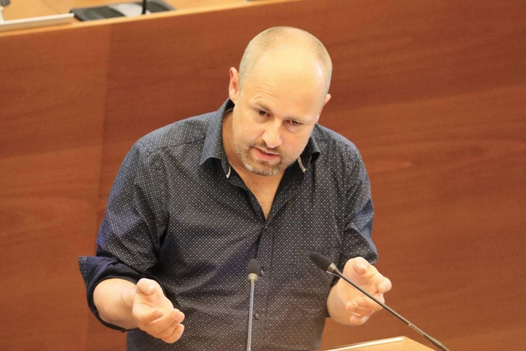 Tobias Peter am Redepult im Leipziger Stadtrat, seine Hände hat er zur Verdeutlichung auf Brusthöhe gehoben.