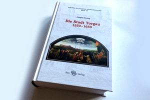 Buch "Die Stadt Torgau 1550 - 1650" von Jürgen Herzog liegt auf einer weißen Oberfläche.