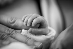 Eine Babyhand umschließt einen Finger eines Erwachsenen