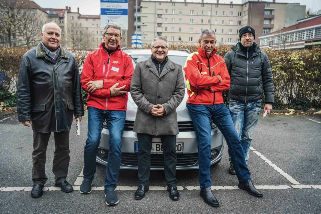 Fünf Männer stehen vor einem Auto