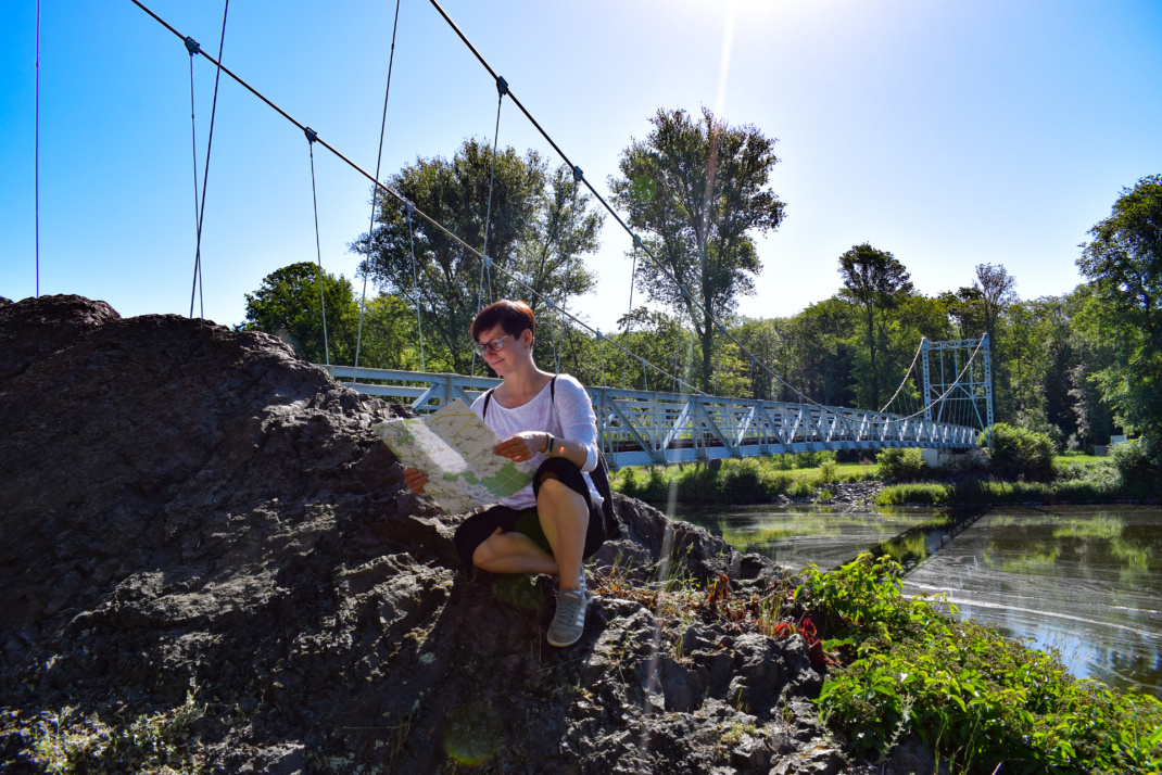 Hängebrücke in Grimma, eine Frau sitzt davor und schaut in eine Landkarte