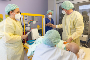 Ein Baby auf einem Behandlungstisch, um den Krankenhausmitarbeiter stehen