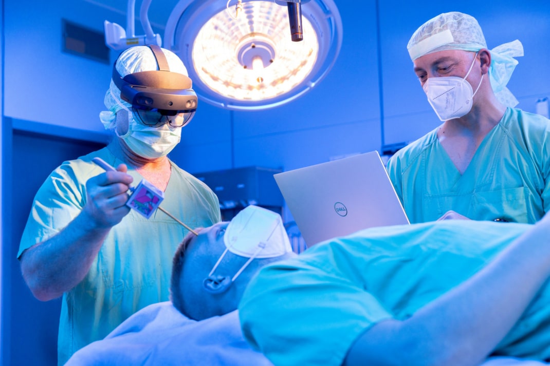 Szene im OP mit einem liegenden Patienten und zwei Ärzten, die ihn ansehen.