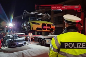 Ein Polizist schaut in Richtung der beiden sichergestellten Autos, der BMW wird gerade auf einen Abschlepper geladen.