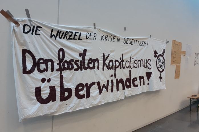 Ein Plakat mit der Aufschrift "Den fossilen Kapitalismus überwinden" vor dem Audimax der Uni Leipzig am 13.12.2022 im Rahmen der Besetzung des klimaaktivistischen Bündnisses "End Fossil: Occupy!"