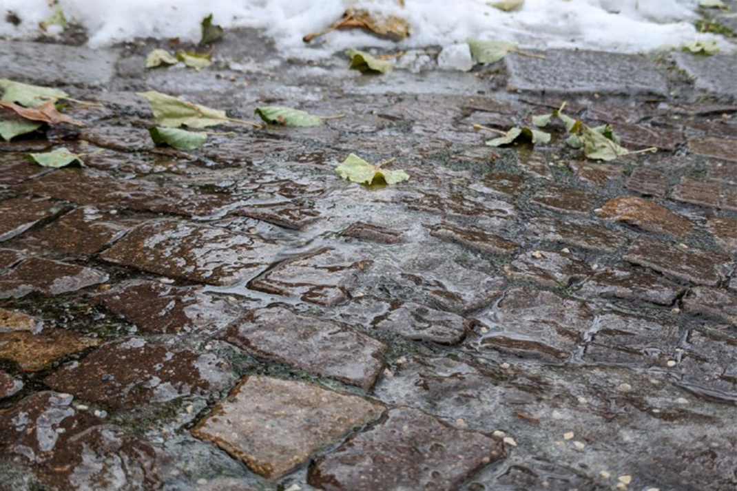 Auf dem Gehweg hat sich eine glatte Eisfläche gebildet.