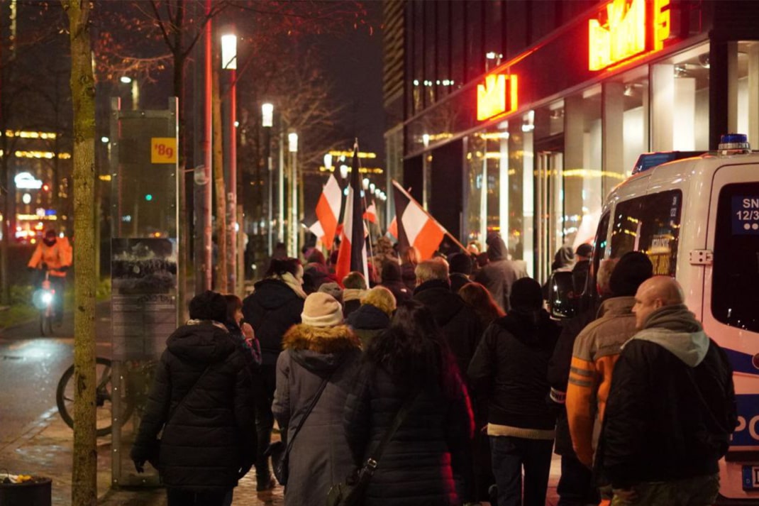 Demo-Teilnehmende laufen auf dem Fußweg neben dem Leipziger Ring am Abend