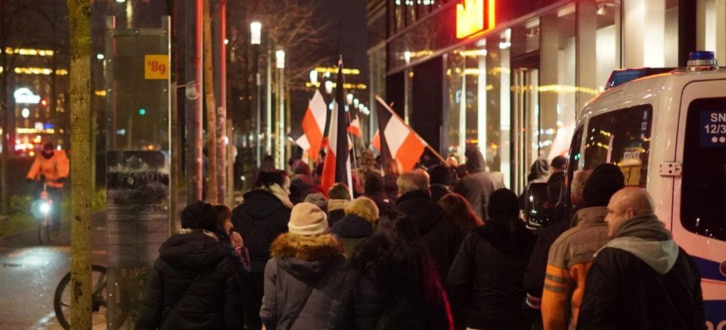 Demo-Teilnehmende laufen auf dem Fußweg neben dem Leipziger Ring am Abend