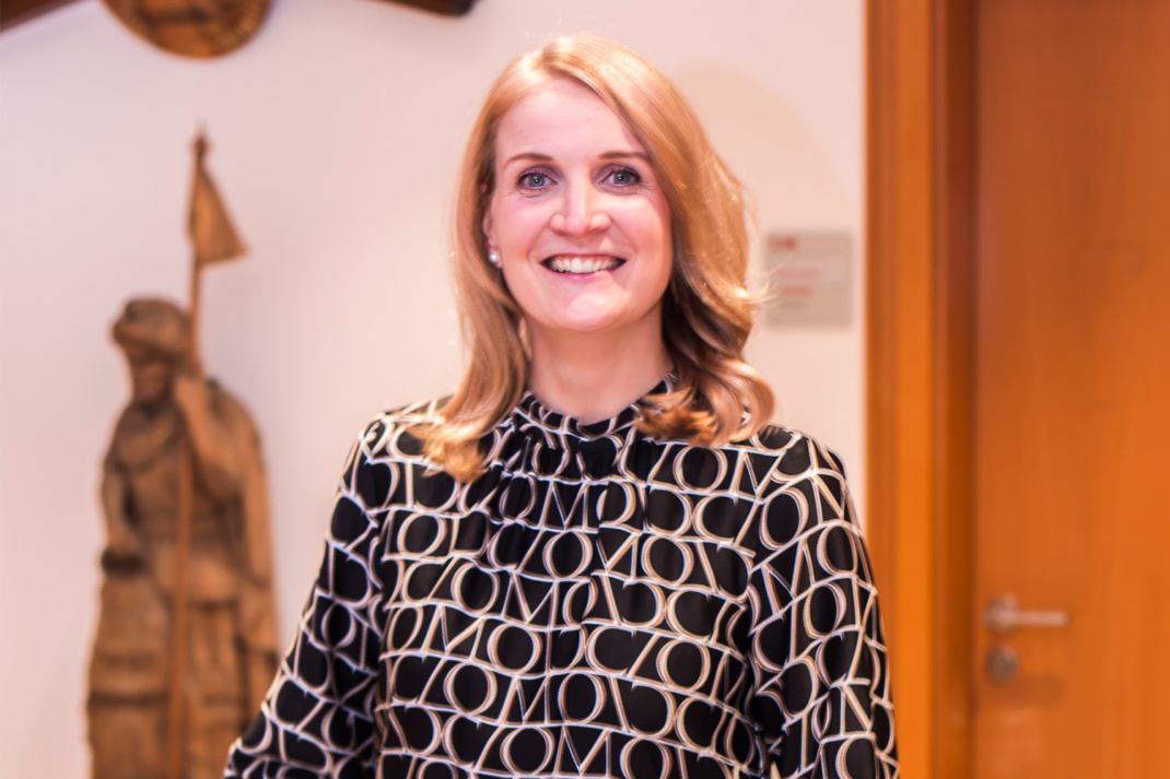 Frau mit blonden Haaren vor Rathauskulisse