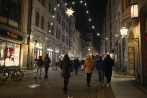 Mehrere Menschen schlendern gemütlich über eine Straße nahe dem Leipziger Weihnachtsmarkt.