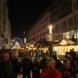 In der Grimmaischen Straße sind mehrere Stände des Weihnachtsmarktes zu sehen, im Hintergrund ein erleuchtetes Riesenrad. Dazwischen spazieren dutzende Menschen in zum Teil weihnachtlicher Kleidung.