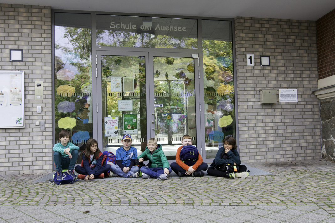 Die Schüler der 4b sitzen auf dem Boden vor der Schule