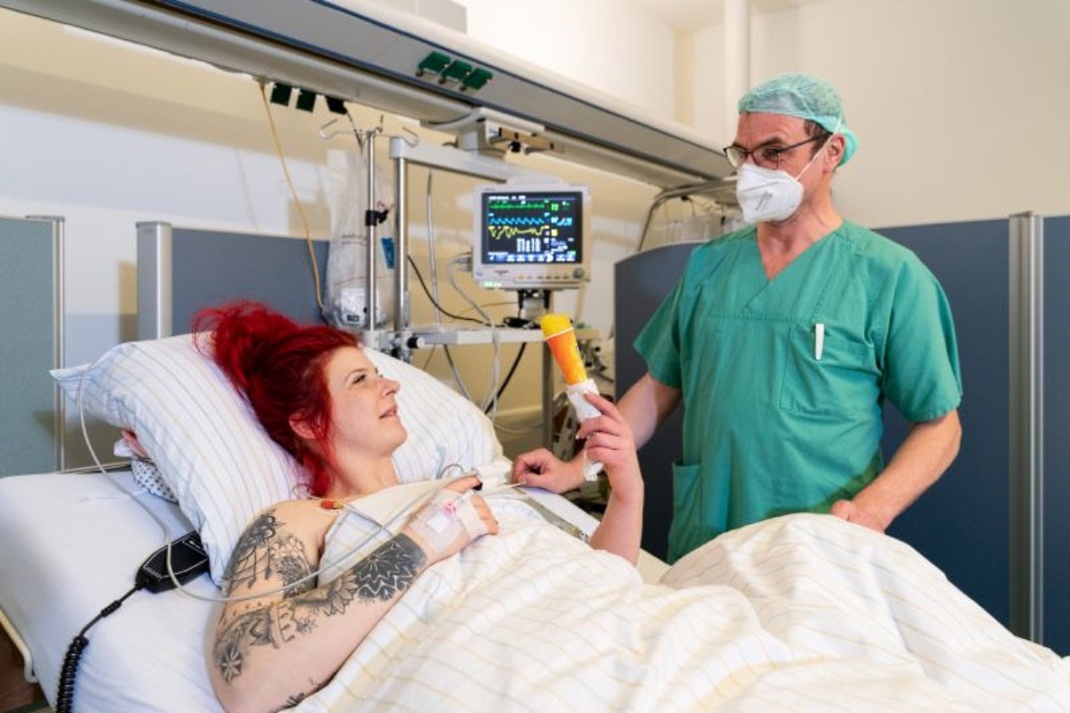 Patientin im Bett mit einem Eis in der Hand und ein Arzt vor dem Bett