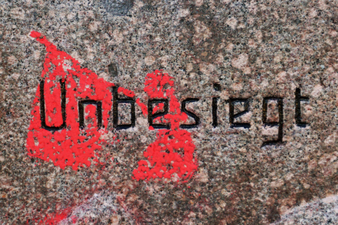 Der Schriftzug "Unbesiegt" auf einem Stein