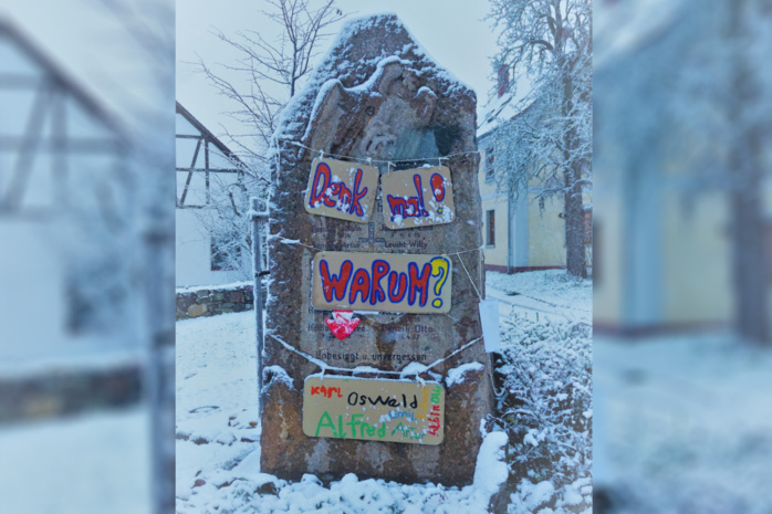 Selbstbemalte Schilder, angebracht an einem Denkmal aus Stein
