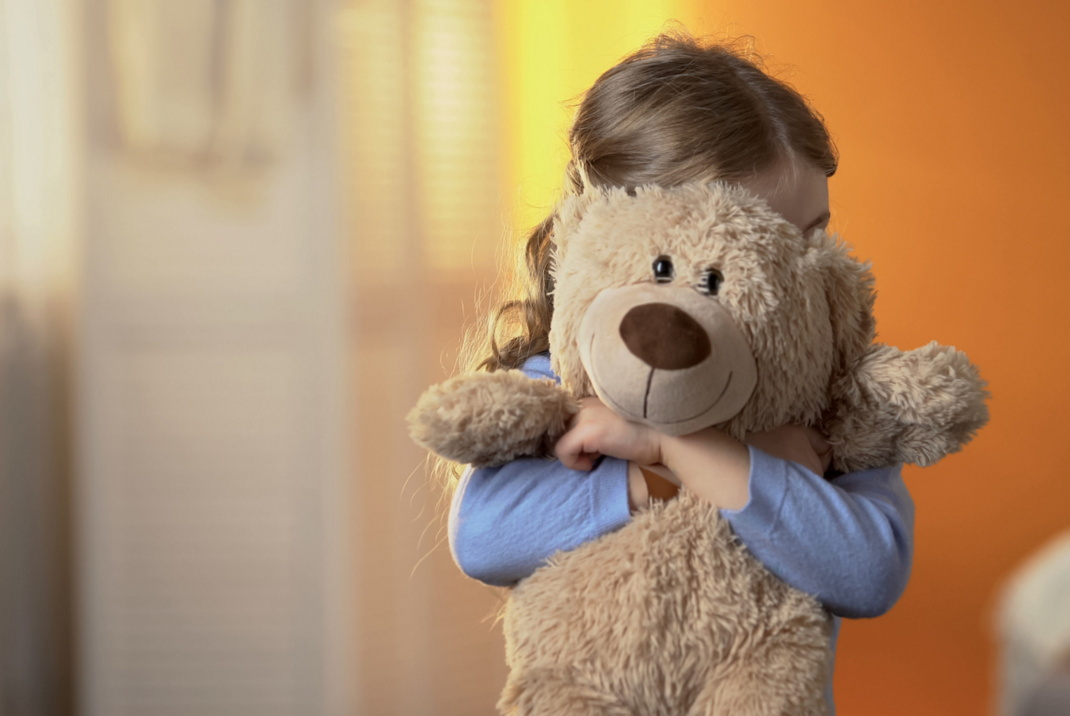 Kind kuschelt sich an Teddybär.