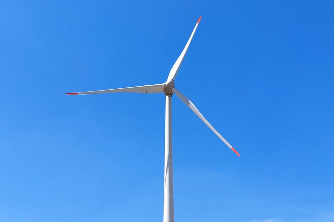 Windrad vor blauem Himmel.