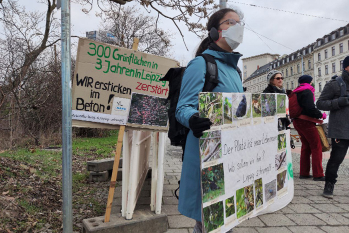 Personen vor einem Zaun mit Protestbanner
