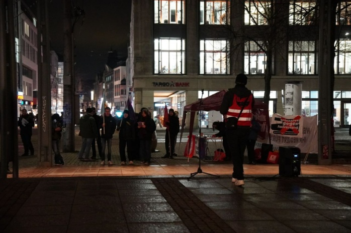 Personen stehen mit Bannern im Protest auf dem Leipziger Augustusplatz
