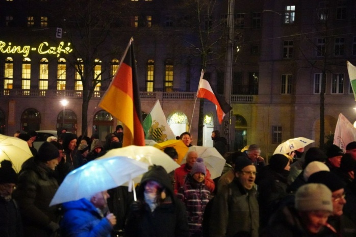 Personen beim Protest mit Fahnen, darunter eine Reichsflagge