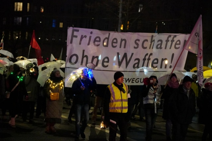 Personen auf dem Leipziger Ring mit Banner, auf welchem steht "Frieden schaffen keine Waffen"