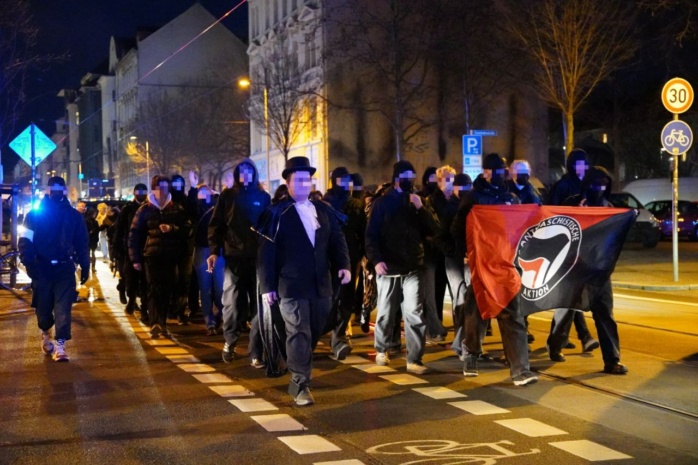 Verkleidete Person mit antifaschistischem Banner