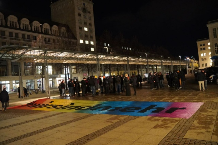 Buntes Banner, daneben Personen gruppe