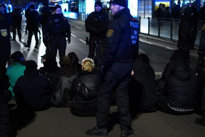 Schwarz gekleidete Personen sitzen auf einer Straße