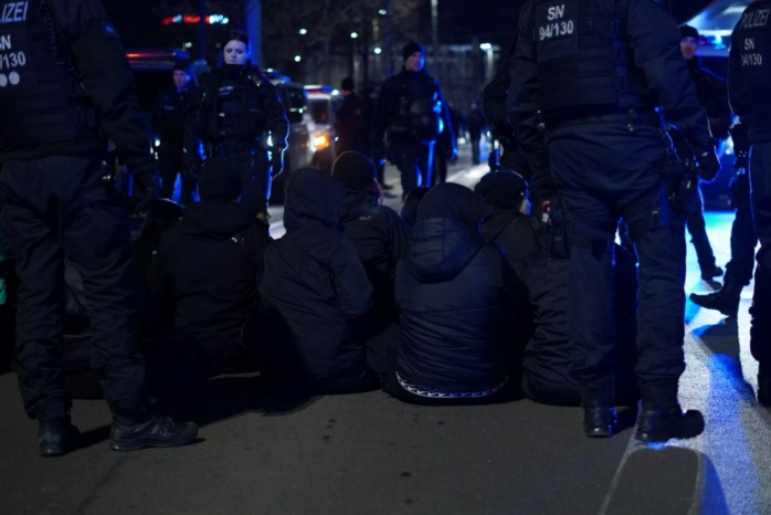 Personen, in schwarz gekleidet, sitzen auf einer Straße