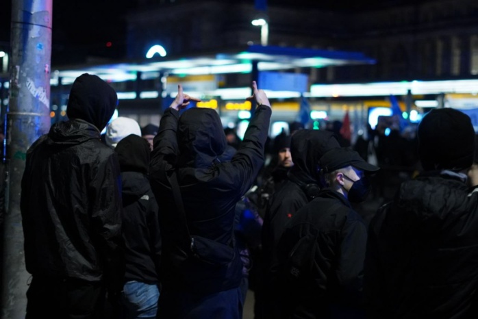 Schwarz bekleidete Personen strecken Mittelfinger heraus
