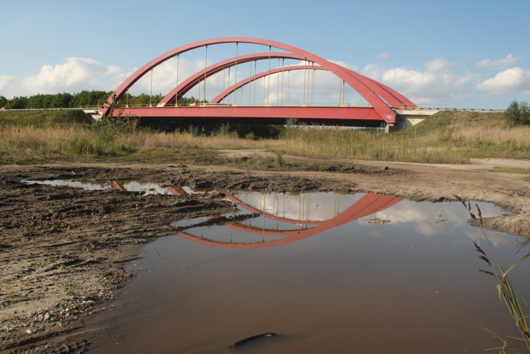 Baugrund mit roter Brücke im Hintergrund.