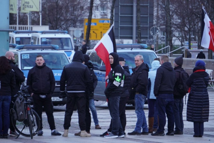 Gruppe von Menschen, einer schwingt eine schwarz-rot-weiße Flagge