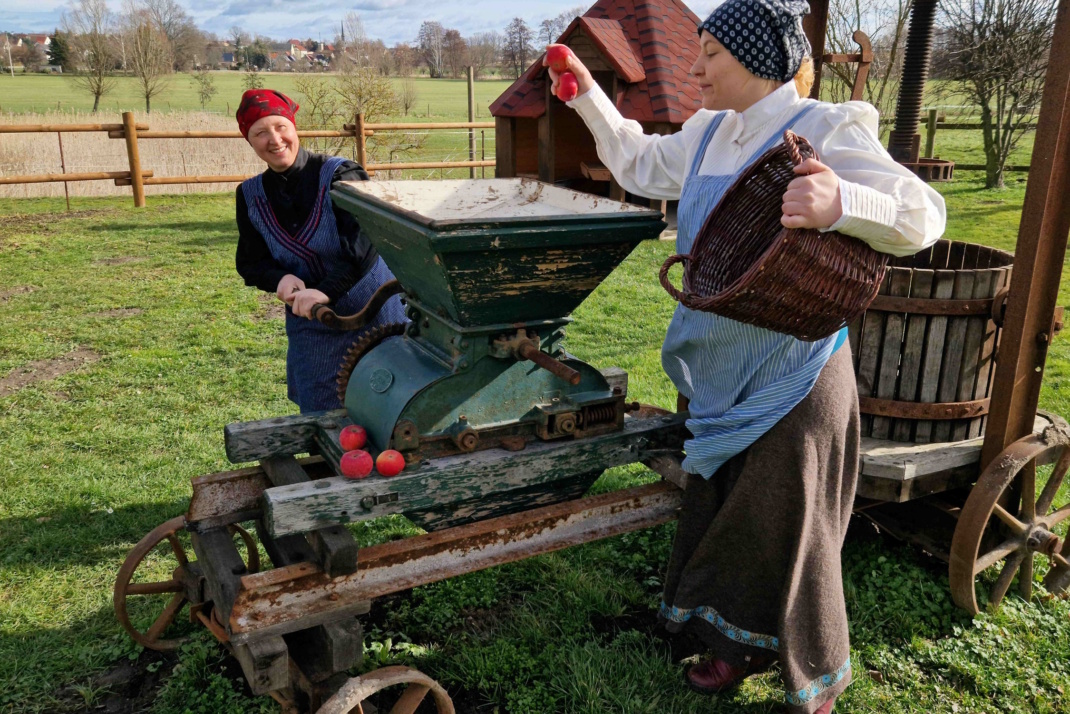 Menschen an alter Apfelpresse.