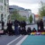 Personengruppe, schwarz gekleidet und mit bunten Fahnen, sitzt auf einer Straße