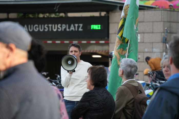 Mann auf einer Bühne spricht in ein Megaphon